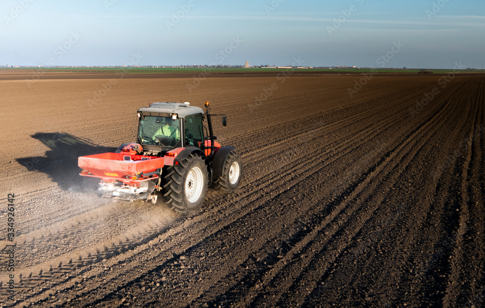 Tractor spreading artificial fertilizers in field Tractor spreading artificial fertilizers in field