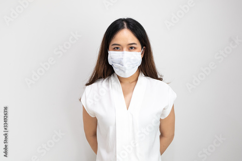 Close up of Asian girl wearing protective mask, with copy space, isolated on white background. Concept of Coronavirus COVID-19 reducing of risk of spreading the infection