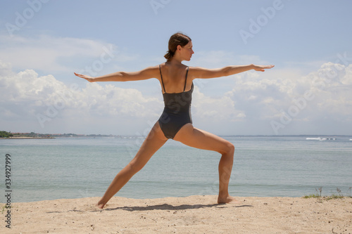 Young woman practising yoga on the beach 