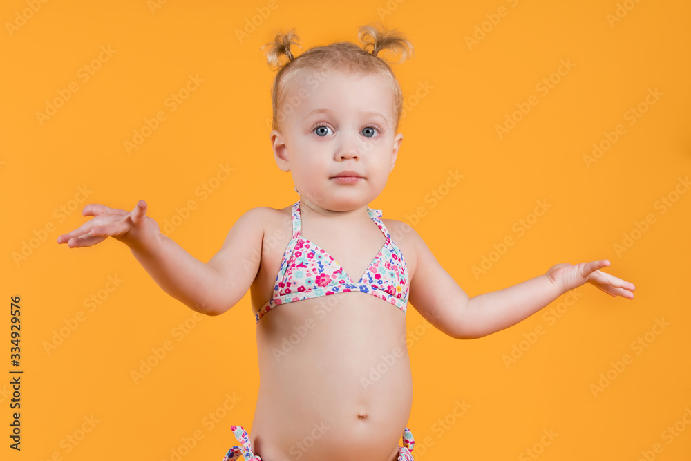 A little girl in a bright swimsuit spreads her arms to the sides A little girl in a bright swimsuit spreads her arms to the sides