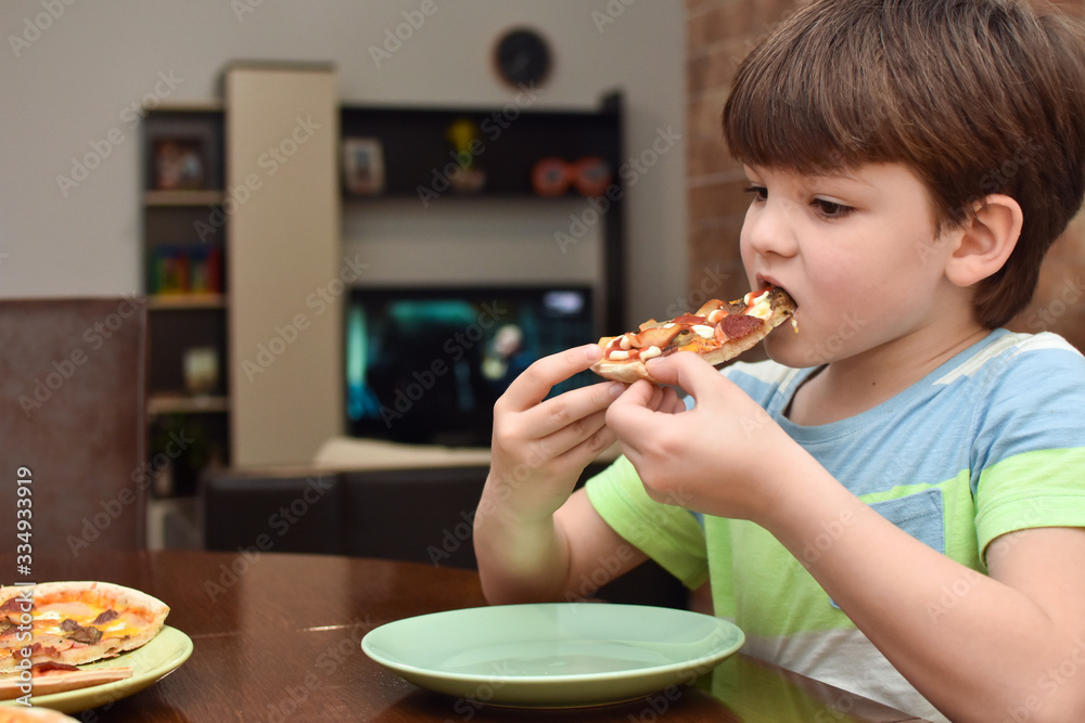 Happy boy eats pizza. Child eating pizza, ordering fast food for dinner Happy boy eats pizza. Child eating pizza, ordering fast food for dinner