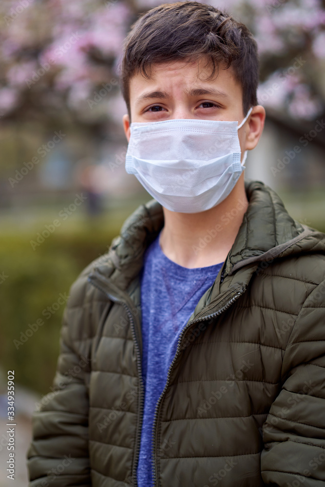 boy with a face mask is in the city outdoor, blooming trees, spring season, flowering time - concept of allergies and health protection from dusty air boy with a face mask is in the city outdoor, blooming trees, spring season, flowering time - concept of allergies and health protection from dusty air