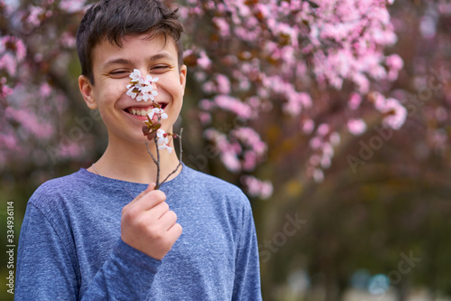 boy with a face mask is in the city outdoor  blooming trees  spring season  flowering time - concept of allergies and health protection from dusty air
