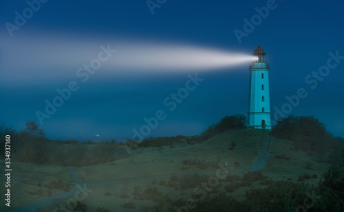 The Dornbusch lighthouse on the German Baltic island of Hiddensee at night. It was a bright winter night by moonlight. There is some fog in the air. That s why you see the light beam very well.