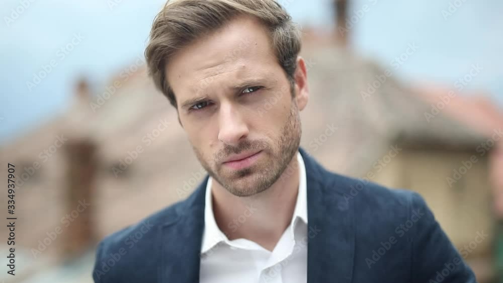 close up of a cool businessman with navy suit standing and staring at camera, outside close up of a cool businessman with navy suit standing and staring at camera, outside