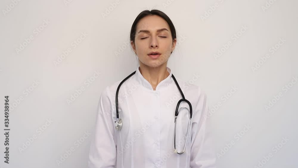 Young woman doctor nurse takes off medical mask. Female breathes deeply and smiling looking at camera. Isolated on white background. Health care and medical concept. epidemic covid-19 end concept Young woman doctor nurse takes off medical mask. Female breathes deeply and smiling looking at camera. Isolated on white background. Health care and medical concept. epidemic covid-19 end concept