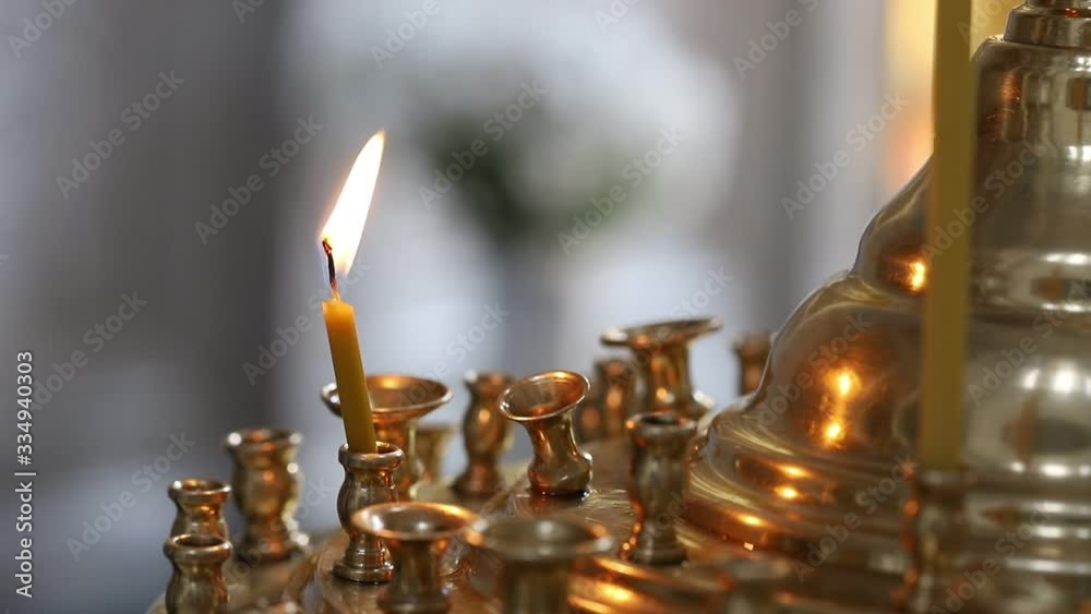 In the Orthodox Church, a lonely small candle burns in a candlestick. Her flame is swinging. The concept of the Orthodox faith. In the Orthodox Church, a lonely small candle burns in a candlestick. Her flame is swinging. The concept of the Orthodox faith.