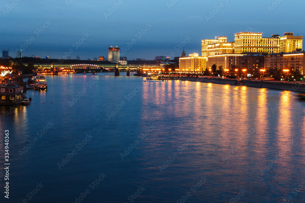 View of the night city from the bridge. Lanterns illuminate the promenade