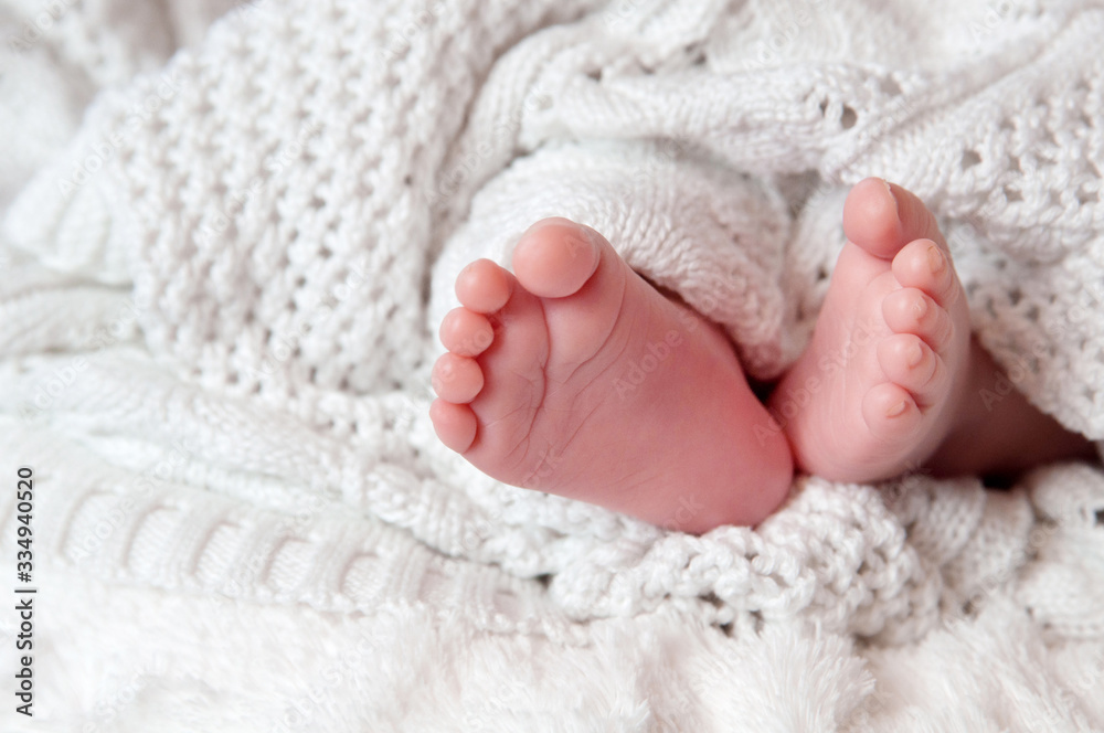 Newborn baby’s legs, toes on the white knitted blanket. Newborn child. Place for a text.