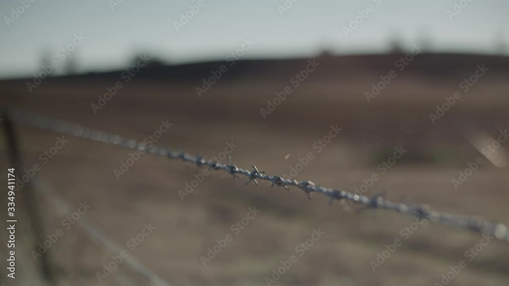 Rack focus from a barbed wire fence to a dry, barren farm paddock Stock ...