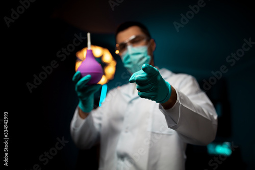 Cropped medical doctor with an enema isolated on dark background