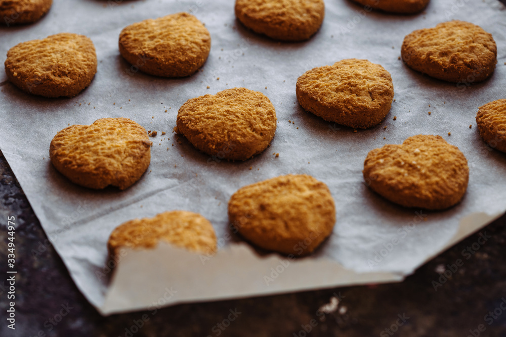 Freshly baked heart-shaped cookies on parchment paper Freshly baked heart-shaped cookies on parchment paper