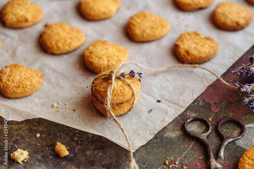 Freshly baked heart-shaped cookies on parchment paper, lavender flower