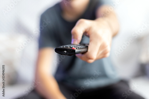 Photo A man sitting on a sofa changes the channel with a remote control