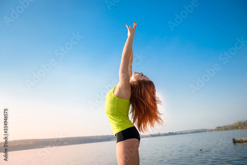 girl in sports uniform resting after morning exercises on the shore of the lake. health and beauty concept. © RomanR