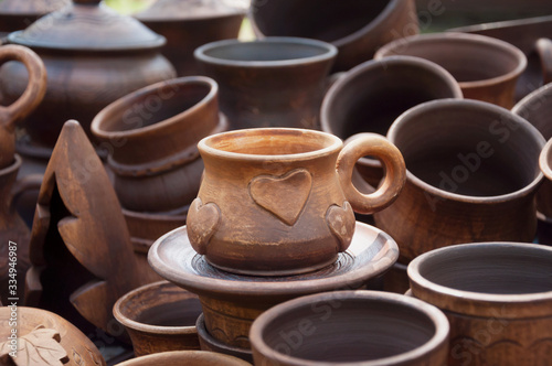 A cup of red clay with a heart. Sale at the fair a large number of diverse in style ceramic cups.