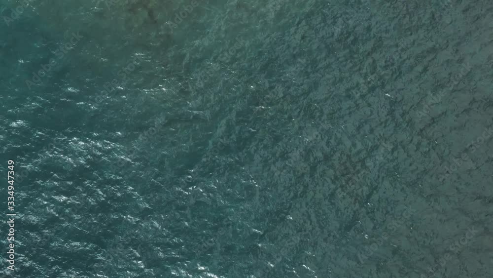 aerial drone overhead view flying up and away from waves water on lake superior revealing sunny shoreline