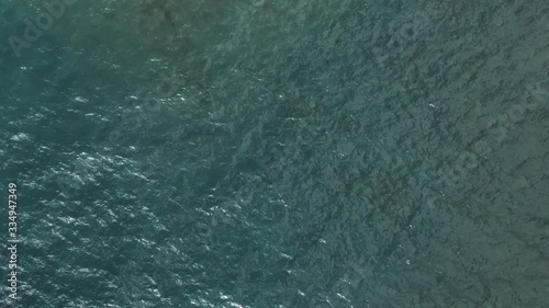 aerial drone overhead view flying up and away from waves water on lake superior revealing sunny shoreline photo