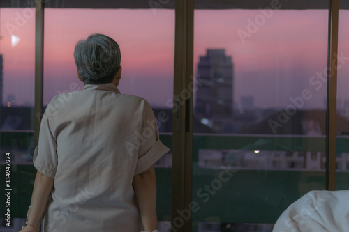 Healthcare medical patient recovering concept, Elderly Asian people sick sitting alone on bed in hospital looking sunshine view when get well after treatment or surgery