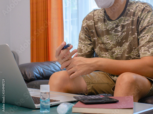 Man Working on Sofa with Mask during COVID-19 Pandemic

A man sitting on a sofa, working on his laptop while wearing a face mask during the COVID-19 pandemic. He is using hand sanitizer and maintainin