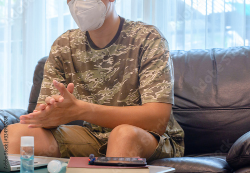 Man Working on Sofa with Mask during COVID-19 Pandemic

A man sitting on a sofa, working on his laptop while wearing a face mask during the COVID-19 pandemic. He is using hand sanitizer and maintainin