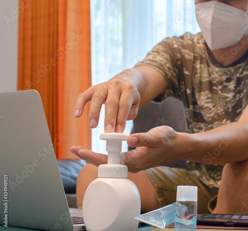 Man Working on Sofa with Mask during COVID-19 Pandemic

A man sitting on a sofa, working on his laptop while wearing a face mask during the COVID-19 pandemic. He is using hand sanitizer and maintainin