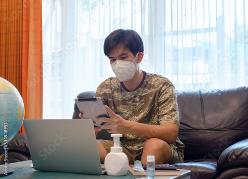 Man Working on Sofa with Mask during COVID-19 Pandemic

A man sitting on a sofa, working on his laptop while wearing a face mask during the COVID-19 pandemic. He is using hand sanitizer and maintainin