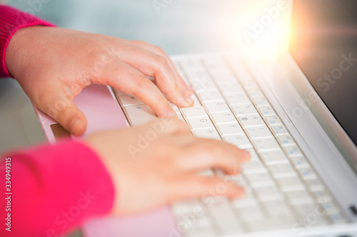 Hands of a schoolgirl typing text on a computer. A schoolgirl is learning lessons using a computer from home.Online concept of school education and social distance during quarantine, self-isolation photo