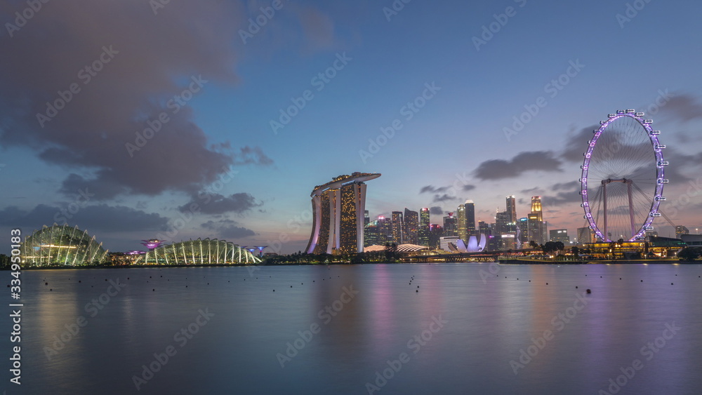Obraz premium Downtown skyline of Singapore as viewed from across the water from The Garden East day to night timelapse. Singapore.