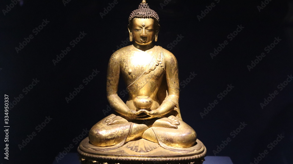 Mumbai, Maharastra/India- March 31 2020: Golden idol of lord Buddha sitting on the ground.