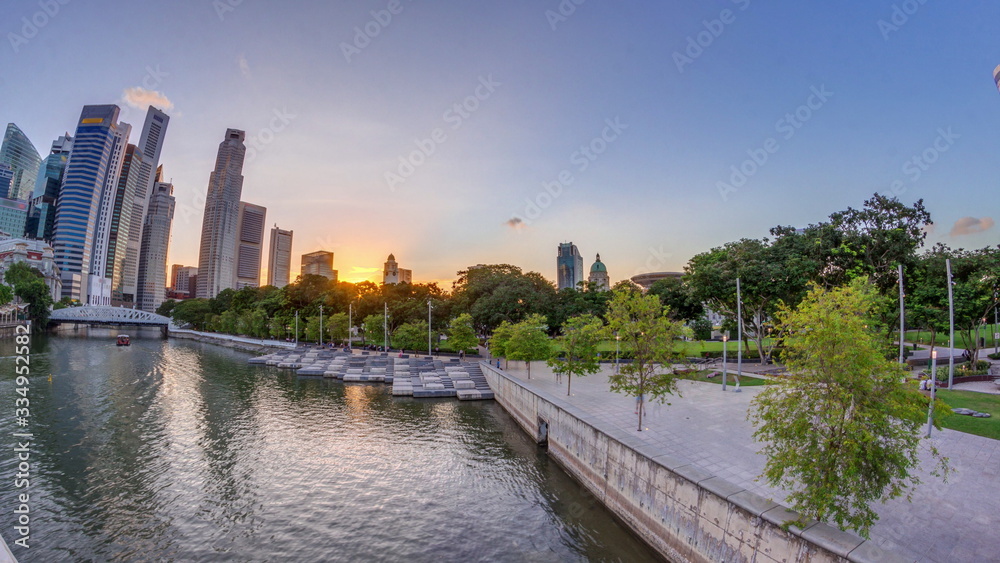 Sunset over Singapore skyscrapers skyline with white Anderson Bridge near esplanade park timelapse.