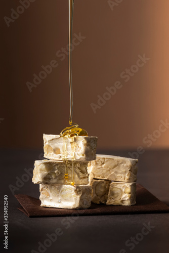 small nougat pieces on dark table with dripping honey