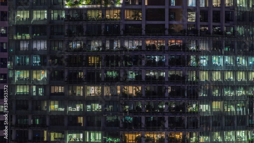 Modern office building with big windows at night timelapse, in windows light shines