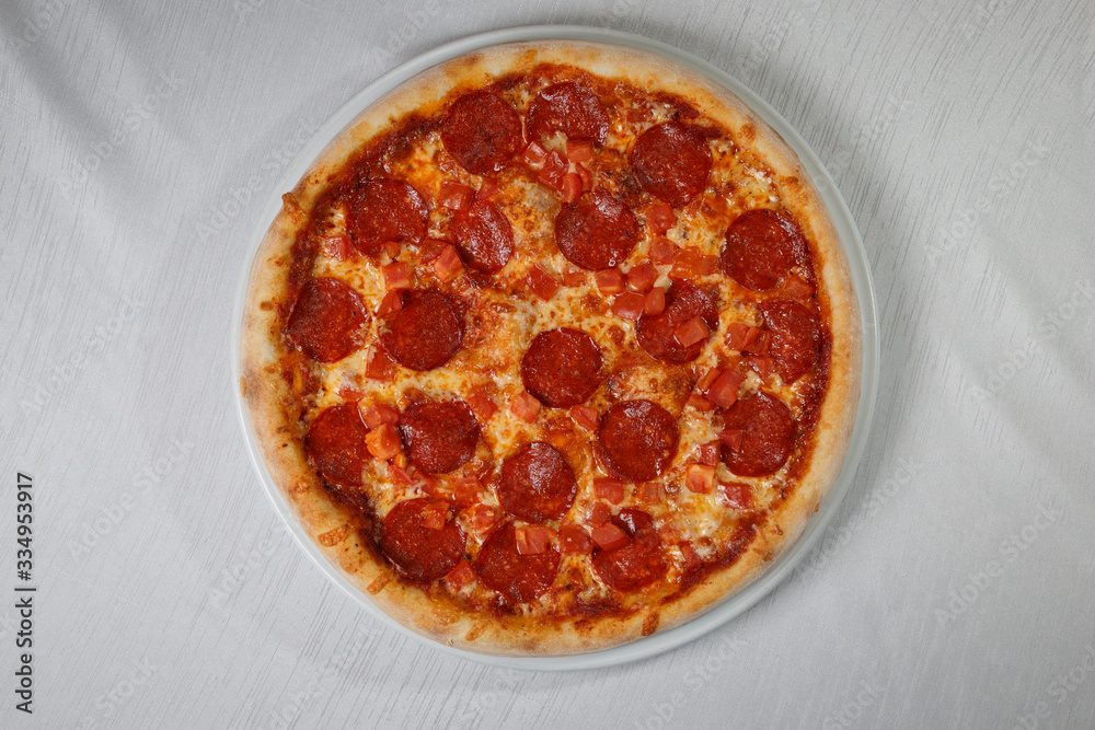 Italian pizza on gray plates on a white plate with spices and seasonings vegetables and meat. Italian pizza on gray plates on a white plate with spices and seasonings vegetables and meat.