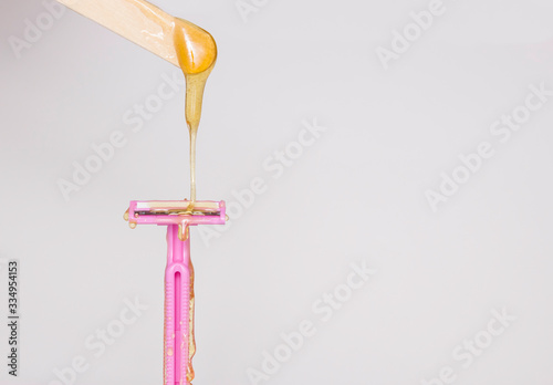 Sugar paste for sugaring or beauty wax flows from a wooden waxing Board to a pink shaving machine. The concept of hair removal . Wax vs razor.