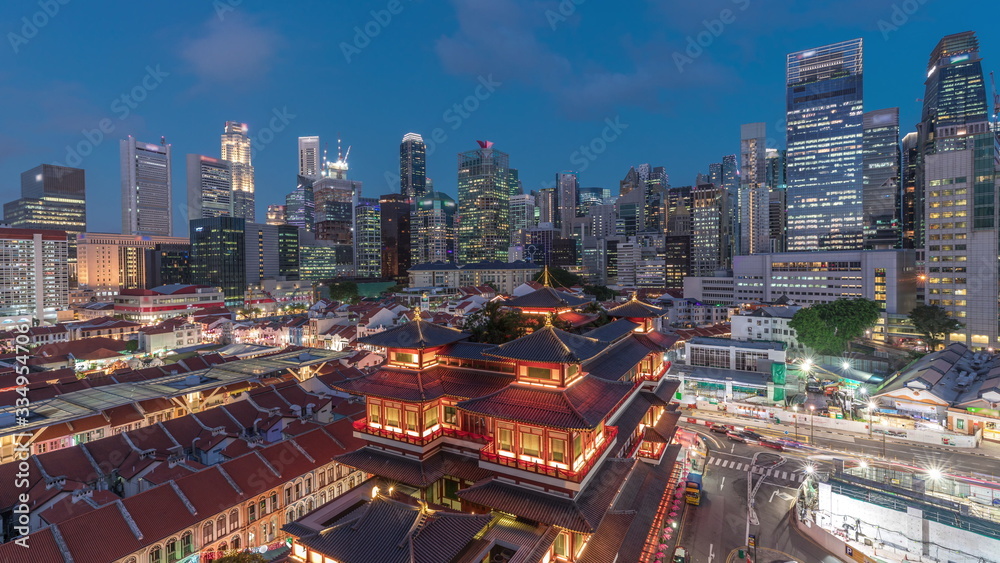 The Buddha Tooth Relic Temple comes alive at night in Singapore Chinatown day to night timelapse, with the city skyline in the background. The Buddha Tooth Relic Temple comes alive at night in Singapore Chinatown day to night timelapse, with the city skyline in the background.