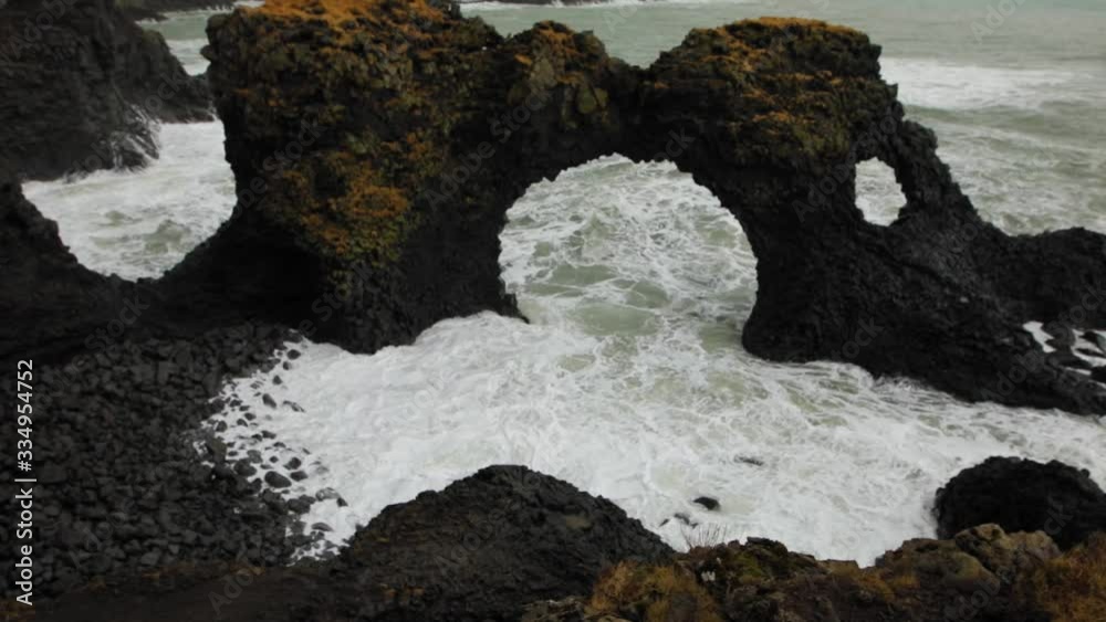 Seeing the stunning arch rock formation by the waves of Iceland - tilt up Seeing the stunning arch rock formation by the waves of Iceland - tilt up