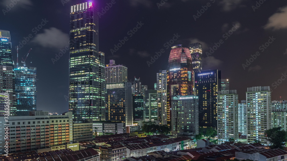 Fototapeta premium Aerial view of Chinatown with red roofs and Central Business District skyscrapers night timelapse, Singapore