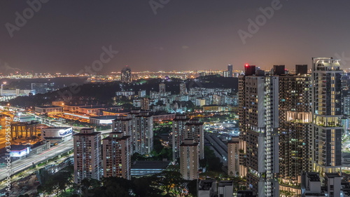 City skyline with commercial port of Singapore aerial night timelapse.