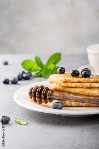 Delicious Tasty Homemade crepes or pancakes with blueberries, honey and mint on white plate. Healthy breakfast concept, gluten free. Copy space.
