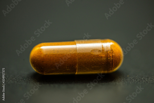 Turmeric capsule and roots curcumin on black background