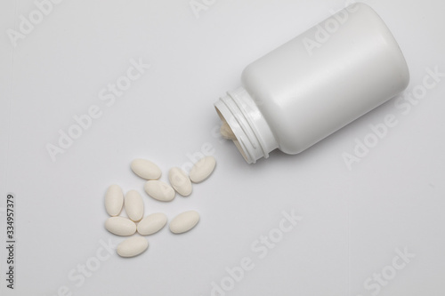 White round tablets covered with a cover are scattered from a plastic can with them. Drugs  pill.