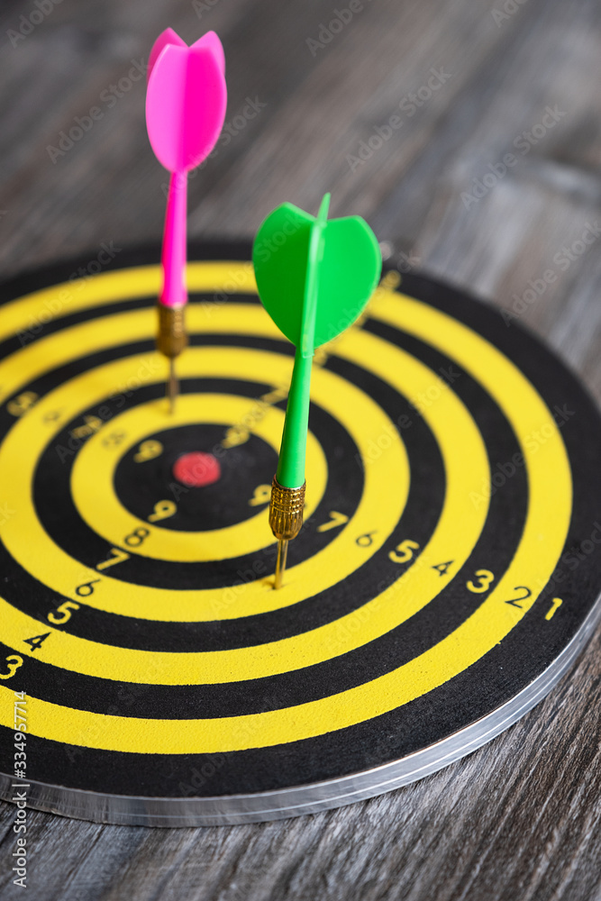 Dart board with colorful darts, on a wooden table. Dart board with colorful darts, on a wooden table.