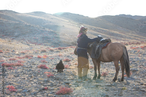 Traditional eagle hunter with his horse and golden eagle. Ulgii, Western Mongolia, Mongolia.
