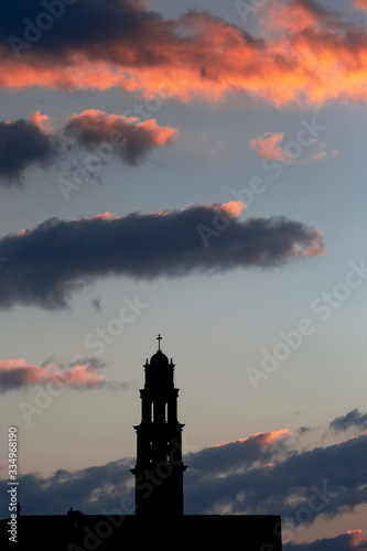 Silhouette of catholic church on dusk cloudscape, rose-colored clouds on purple sunset sky
