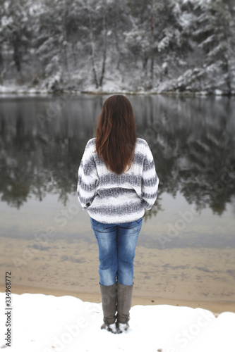vertical photo of a beautiful long-haired brunette on a background of a winter river © Serafima