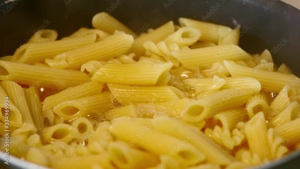 Cooking penne rigate close up shot. Steam over the pasta. Preparing traditional Italian dish. Cooking penne rigate close up shot. Steam over the pasta. Preparing traditional Italian dish.