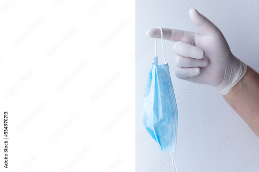 A male hand in medical gloves holds a protective medical mask. Pandemic virus. Copy space. A male hand in medical gloves holds a protective medical mask. Pandemic virus. Copy space.