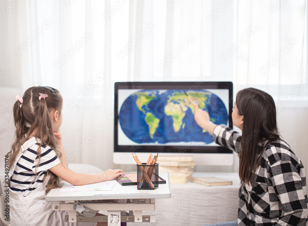 A mother with a child sits at the table and does homework. The child learns at home. Home schooling. A mother with a child sits at the table and does homework. The child learns at home. Home schooling.
