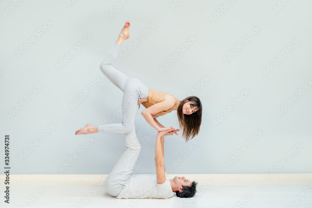 Athletic young couple practicing partner yoga at gym, sitting on